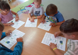 Dzieci wodzą rękami po muzografie do piosenki „Nad stawem”.