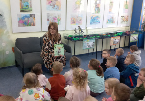 Pani bibliotekarka prezentuje książkę o dinozaurach.