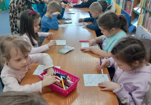 Przedszkolaki rozwiązują ćwiczenia o dinozaurach.