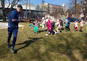 Przedszkolaki biegną za wężem z liny.