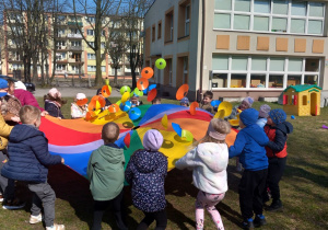 Dzieci podrzucają krążki na chuście animacyjnej.