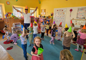 Dzieci wraz z panem Damianem chodzą w czapeczkach - rożkach na głowie