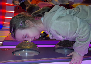 Kornelia obserwuje w półokrągłych kopułach animacje świetlno-dźwiękowe przedstawiające zmieniające się obrazy żywiołów i natury.