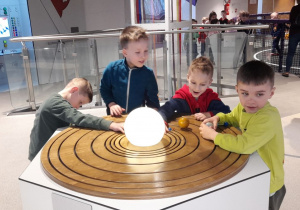 Franek, Julian, Leon i Kacper poznają model Układu Słonecznego, przesuwając planety po orbitach wokół świecącego Słońca.