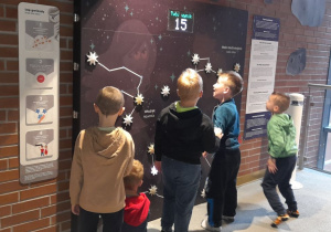 Chłopcy biorą udział w zadaniu na czas, dotykając podświetlanych gwiazd i odtwarzając układ gwiazdozbioru.