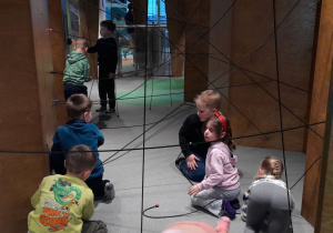 Dzieci przechodzą przez „pajęczynę” z rozpiętych linek, ćwicząc zręczność, koncentrację i koordynację ruchową.