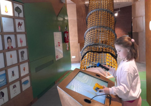 Lilia obserwuje na ekranie, jak specjalna kamera pokazuje temperaturę różnych przedmiotów.