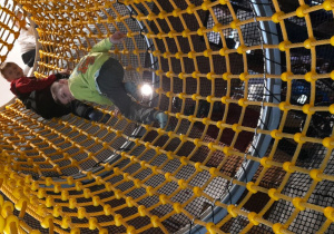 Antoś i Kacper wspinają się w tunelu z siatki.