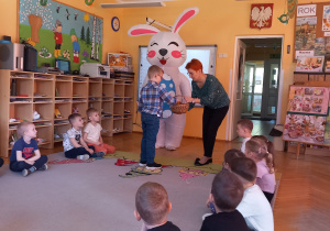 Maciek wyciąga z koszyczka jajko z zagadką.