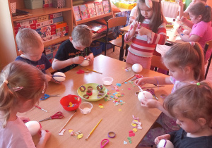 Przedszkolaki dekorują styropianowe jajka.