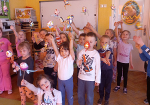 Krasnoludki pozują do zdjęcia z pisankami na patyczku.