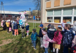 Dzieci witają się z Zajączkiem w ogrodzie przedszkolnym.