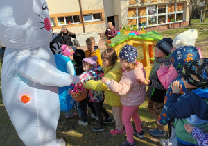 Wielkanocny zajączek częstuje dzieci z grupy misiaczków słodkimi jajeczkami.