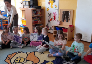 Pani Izabela rozdaje milusińskim powiększone grafiki banknotów i bilonu.