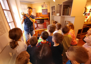 Kustosz prezentuje dzieciom lampę naftową.