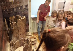 Dzieci oglądają naczynia ceramiczne, studnie z epoki brązu oraz eksponaty z kultury łużyckiej.