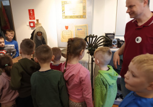 Dzieci oglądają przedmioty zgromadzone w zakładach rzemieślniczych – fryzjera, krawca.