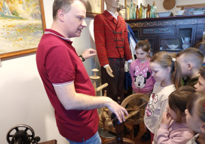 Dzieci oglądają kołowrotek i poznają jego przeznaczenie oraz strój sieradzki.