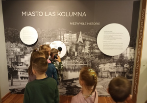 Sześciolatki oglądają wystawę Miasto Las - Kolumna Niezwykłe Historie.