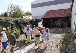 Krasnoludki idą za kustoszem przez dziedziniec Muzeum.