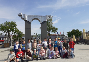 Grupa „Krasnoludków” stoi przed Pomnikiem Walczącym o Niepodległość Ojczyzny.