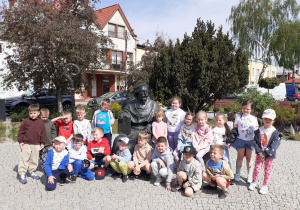 Dzieci pozują do zdjęcia pod pomnikiem Jana Łaskiego.