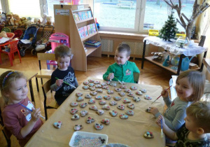 Pięcioro dzieci z grupy Krasnoludków dekoruje ciastka.