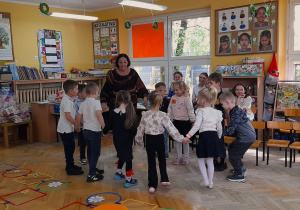 Dzieci tańczą w kole z prowadząca panią Haliną Janus-Wódka.