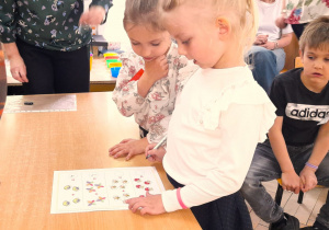 Dziewczynki rozwiązują zadanie matematyczne przy stoliku.