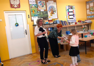 Pani Agnieszka Siemińska i pani Dyrektor Zofia Molenda-Kimla wręczają uczestniczce gry nagrodę dla przedszkola i dyplom.