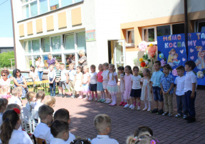 Grupa „Słoneczka” stoi i recytuje wiersz „Uwaga! Uwaga!”.