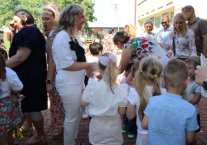 Pani dyrektor częstuje cukierkami wszystkie dzieci i rodziców.