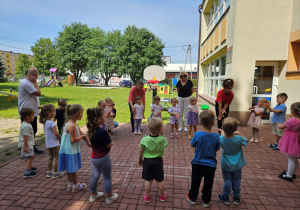 Dzieci stoją w kole i naśladują biedronkę z rymowanki