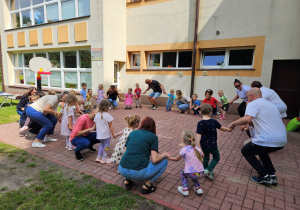 Panie wraz z dziećmi, rodzicami i dziadkami przewracają się podczas zabawy "Kółko graniaste"