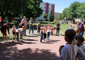 Dzieci i dorośli podczas zabawy ruchowej do piosenki: "Głowa, ramiona, kolana, pięty...".