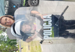 Julia wciela się w rolę policjantki, prezentując kask z przyłbicą i tarczę ochronną.