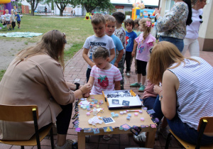 Mama Franka i Antosi malują dzieciom kolorowe tatuaże.