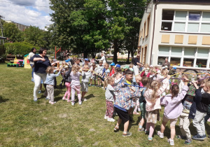 Przedszkolaki obracają się trzymając gumę rękami.