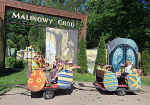 Zadowoleni pasażerowie machają z wagoników pociągu.
