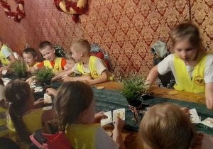 Przedszkolaki przygotowują „medale mocy”, ozdabiając drewniane medale wybranymi obrazkami.