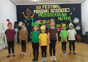 Uczestniczki festiwalu na tle dekoracji XX Festiwalu Piosenki Dziecięcej „Przedszkolna Nutka”.