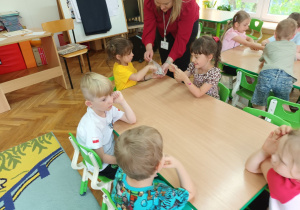 Pani Patrycja rozdaje dzieciom kolorowe naklejki.