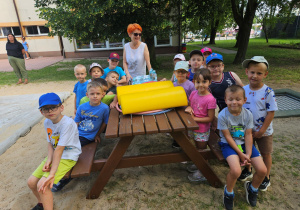 Dzieci z grupy "Krasnoludki" siedzą przy stoliku na placu przedszkolnym