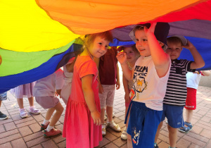 Dzieci z grupy "Biedronek" chowają się pod chustą animacyjną