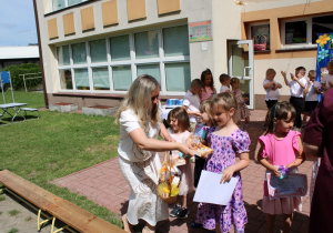 Anastazja odbiera od Pani Zosi słodki upominek.