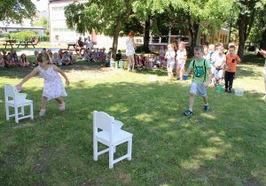 Starszaki na wyścigi przenoszą wodę kubkami do wiaderka.