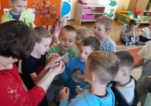 Pani Klaudia prezentuje dzieciom metalową końcówkę rękawa cukierniczego, wykorzystywaną do dekorowania wypieków.