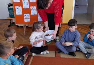 Pani Klaudia częstuje dzieci przygotowanymi przez siebie wypiekami.