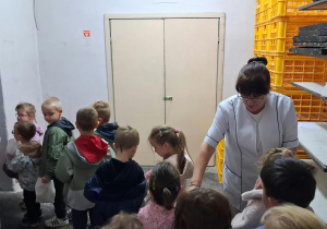 Pani piekarz wręcza dzieciom paczuszki z pieczywem na II śniadanie.