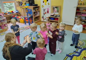 Przedszkolaki odczymują pieczątki na rączki.